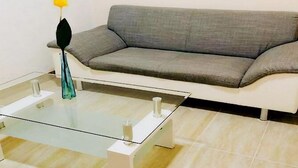 A modern living room with a grey sofa, a glass coffee table, and a vase with a yellow flower. - Apartment in Gammertingen With Terrace (Gammertingen)