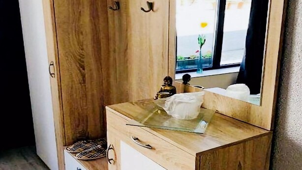 A wooden wardrobe with a mirror, a small statue, and a glass-topped dresser. - Apartment in Gammertingen With Terrace (Gammertingen)
