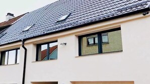 A two-story building with a light-colored facade, a dark roof, and a garage door. - Apartment in Gammertingen With Terrace (Gammertingen)