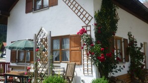 A traditional chalet with wooden shutters, a balcony with a lattice, and a rose bush climbing the wall. - Farmhouse Near Oberammergau (Unterammergau)