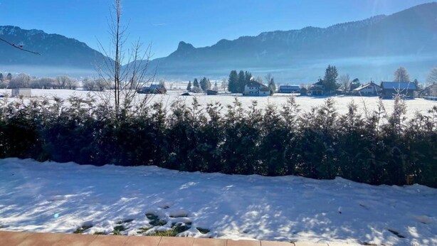 A snowy landscape with a clear sky, mountains in the background, and a few buildings. - Farmhouse Near Oberammergau (Unterammergau)