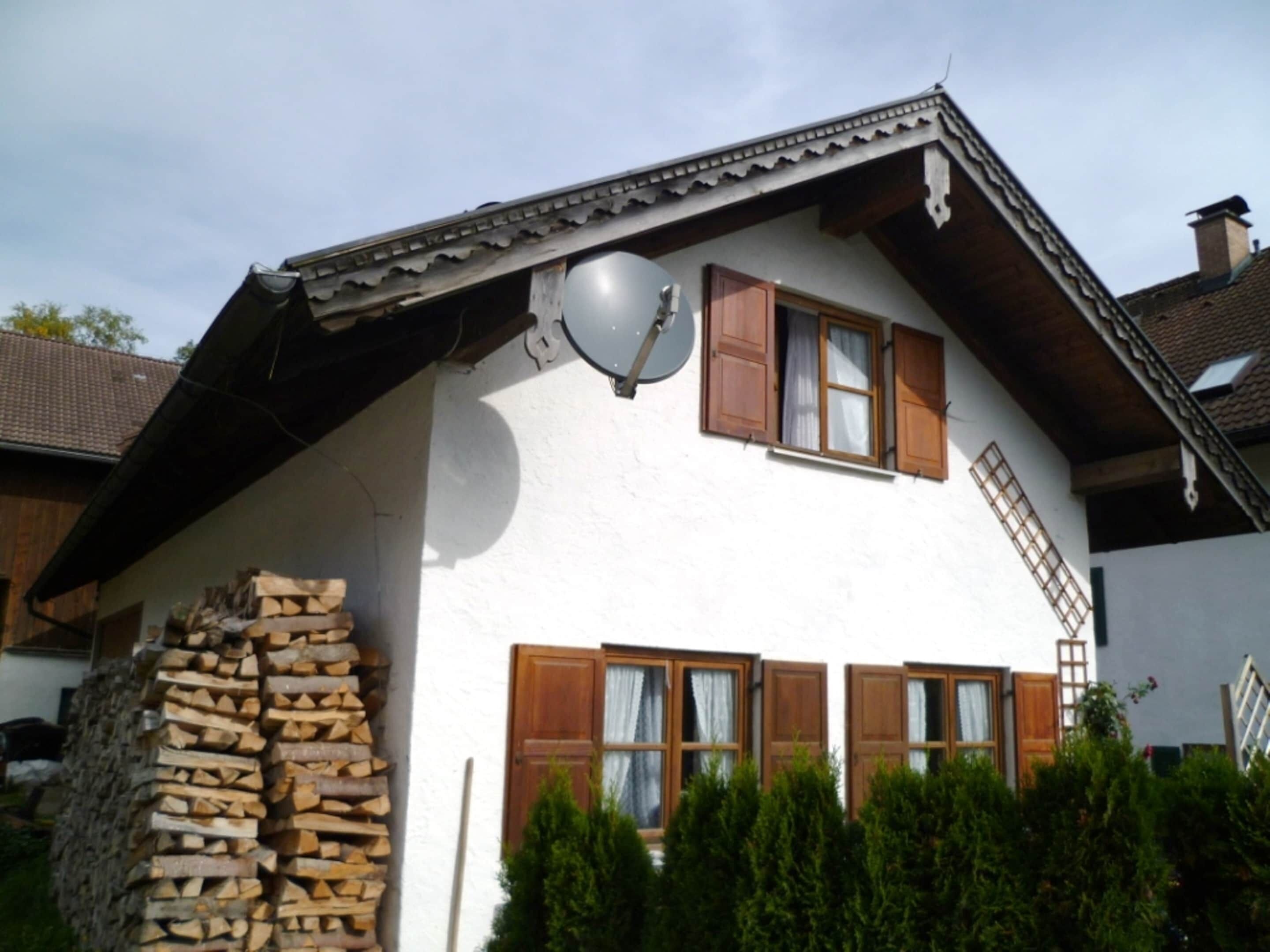 A traditional chalet with a sloped roof, wooden shutters, and a satellite dish.