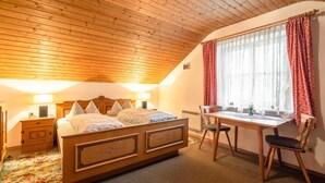 A bedroom with a wooden ceiling, a bed with a headboard, a desk, and a chair. - Farmhouse Near Oberammergau (Unterammergau)