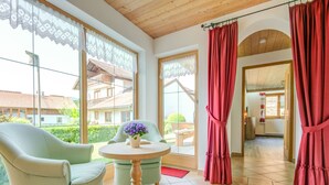 Una habitación con un ventanal grande, una mesa con un florero y una silla.
