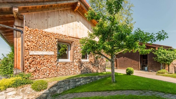Una casa de madera con un muro de piedra y una ventana.