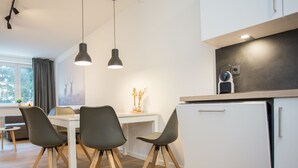 Une cuisine moderne avec un coin repas, comprenant un plan de travail blanc, des meubles en bois et une table à manger avec quatre chaises.