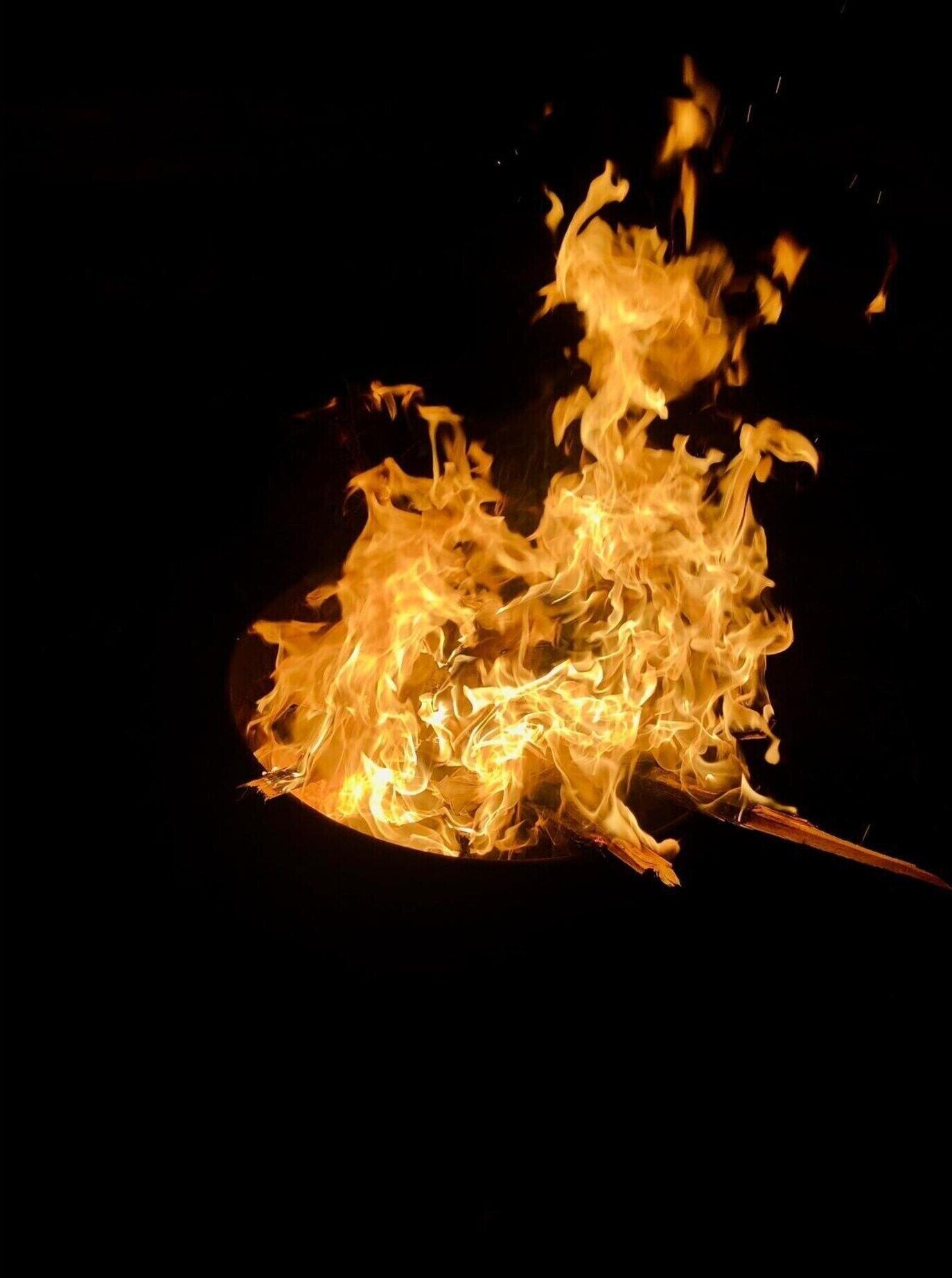 Et nærbillede af ild med flammer og gløder mod en mørk baggrund.