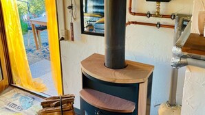 A wood-burning stove with a chimney, a door leading outside, and a view of the outdoors. - Ferienhaus, Schontal-winzenhofenn (Schöntal)