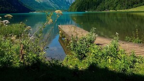 A serene lake with a wooden dock, surrounded by lush green mountains and clear blue sky. - Holiday Flat in Schonau am Konigssee (Schoenau am Koenigssee)