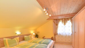Une chambre confortable avec un plafond en bois et un grand lit recouvert d’une literie verte et blanche.