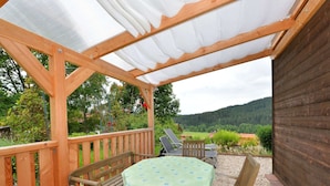 Une terrasse en bois avec une table et des chaises, offrant une vue sur un paysage magnifique.
