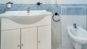 Une salle de bain avec un lavabo blanc, un bidet et un porte-serviettes.