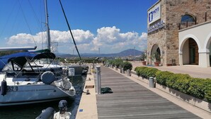 Un puerto deportivo con barcos amarrados, un edificio de piedra con un cartel y un cielo despejado.