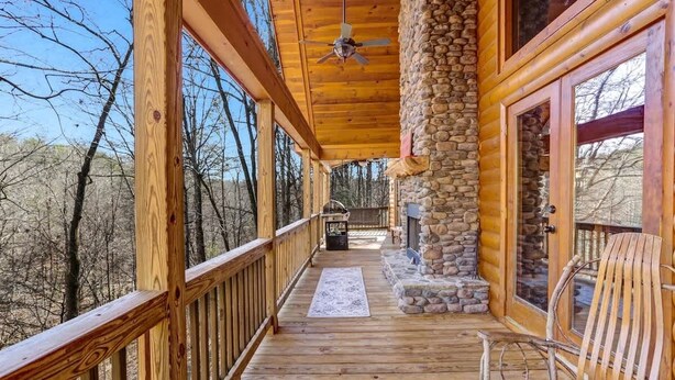 Une terrasse en bois avec un pilier en pierre, une rambarde en bois et un banc.