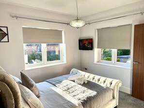 A bedroom with a bed, two windows, a TV, and a door. - Chilton View - Luxury Home in County Durham, 4bed (Chilton)