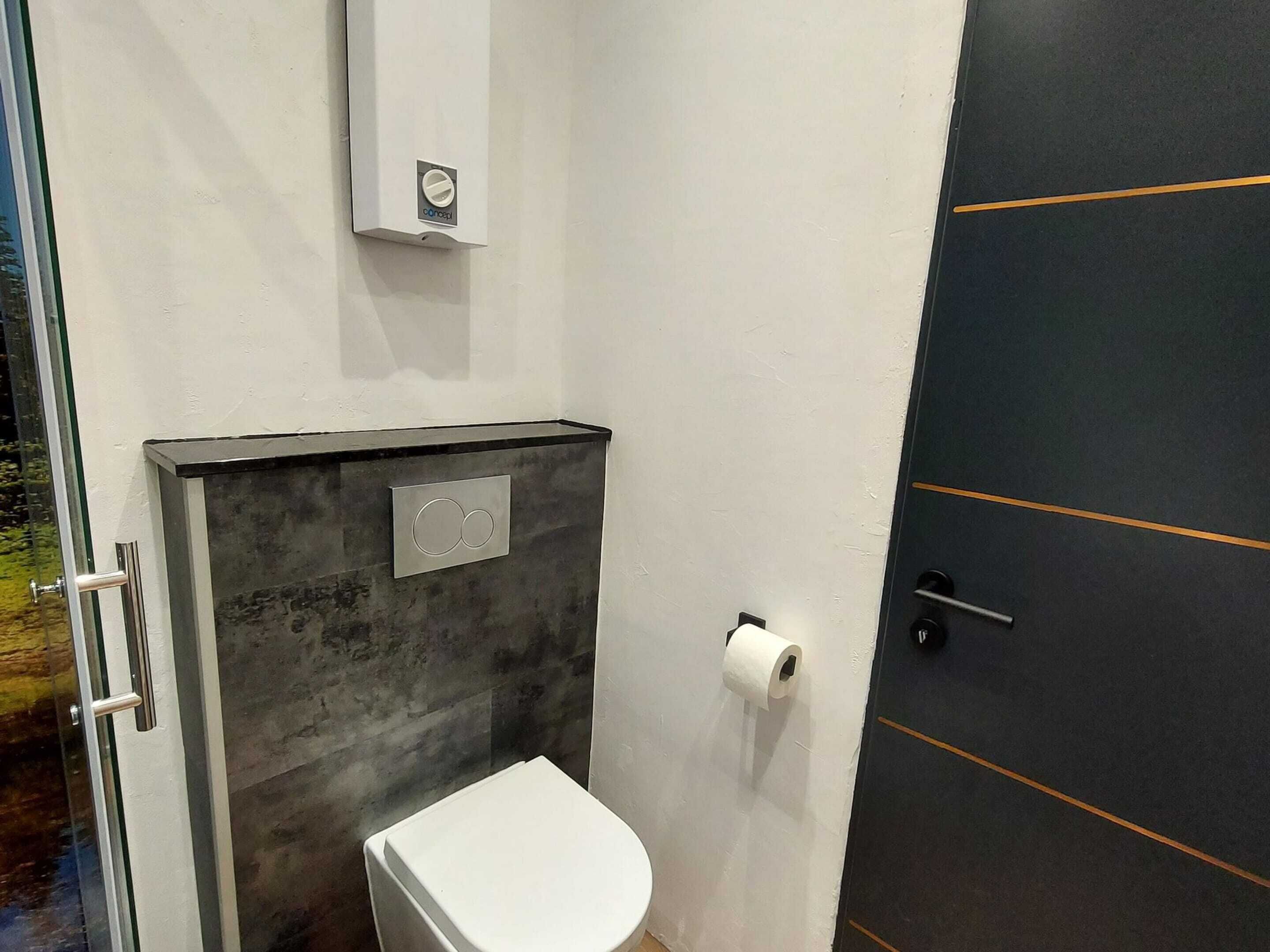 A compact bathroom with a toilet, a towel rack, and a wall-mounted toilet paper holder.