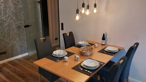 A dining area with a wooden table set for four, black chairs, and a basket of bread. - Moderne Wohnung in Winterberg Nahe Skigebiet (Winterberg)