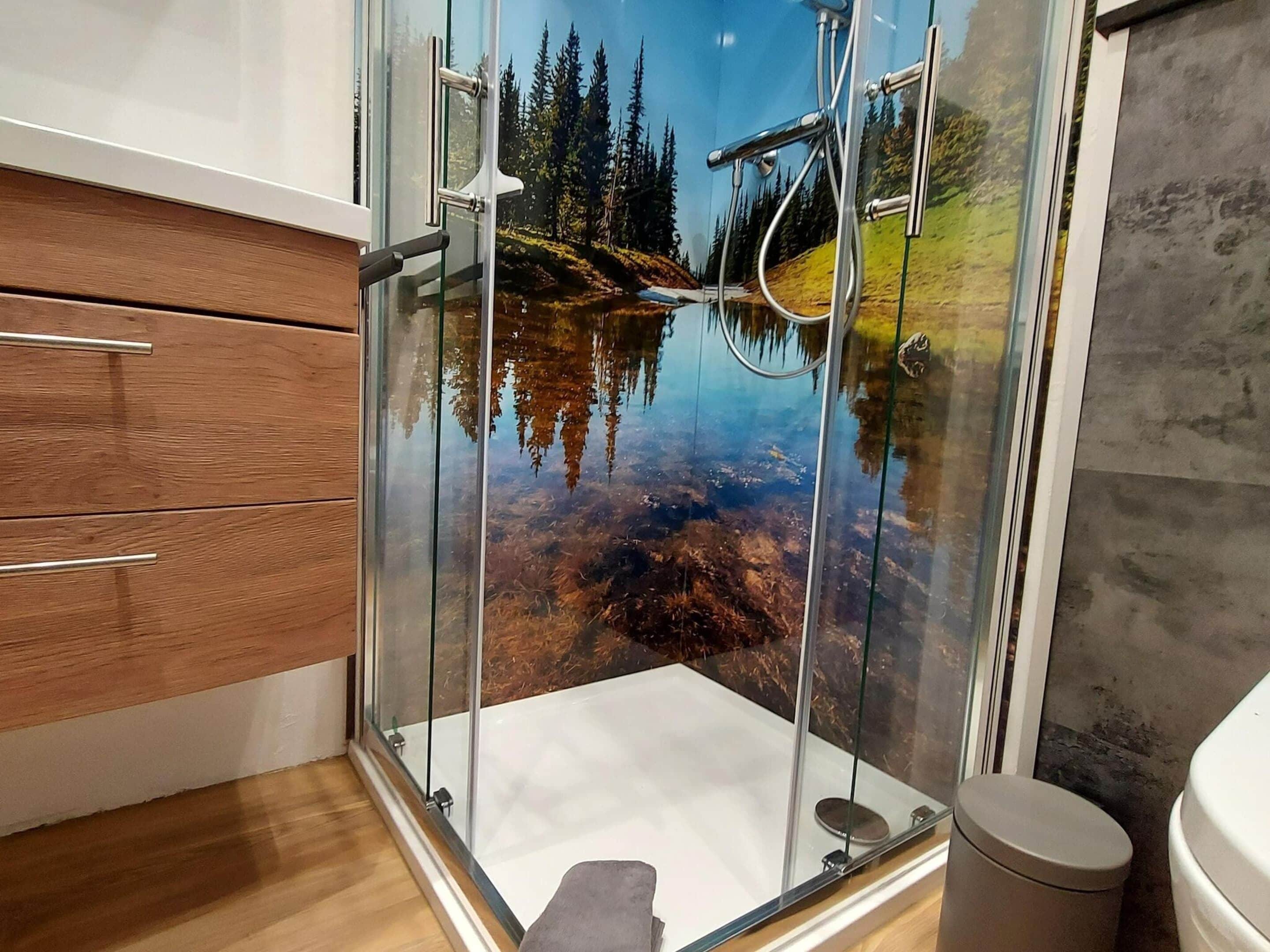 Ein Badezimmer mit Duschkabine aus Glas, Holzschrank und Marmorplatte.
