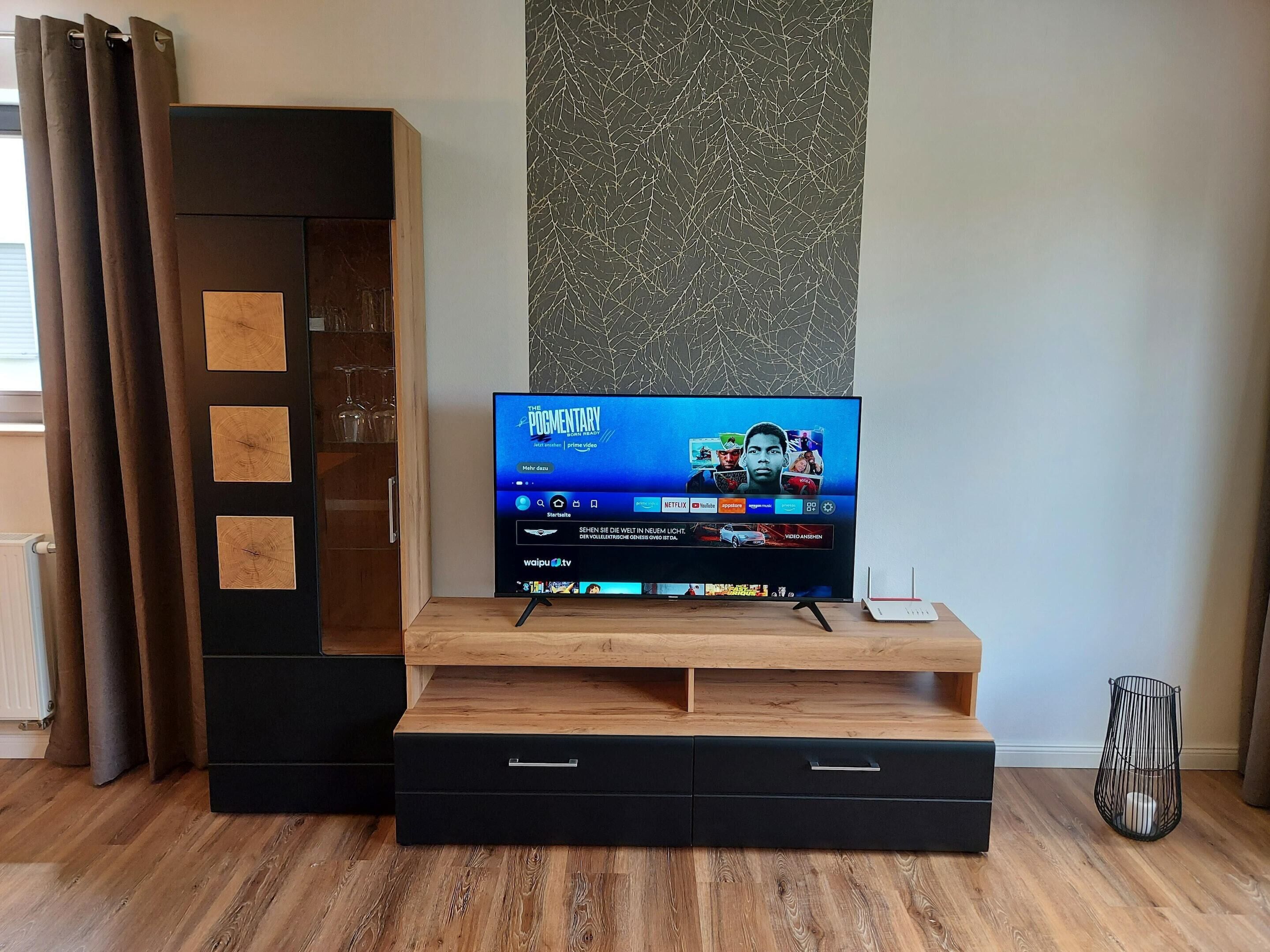 Un mueble moderno de entretenimiento con un televisor de pantalla plana mostrando la interfaz de un servicio de streaming.