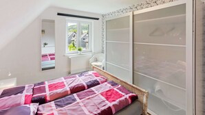 Une chambre à coucher avec un lit, une fenêtre donnant sur un beau paysage, un radiateur et une armoire.