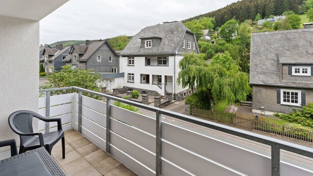 Un balcon donnant sur un quartier résidentiel, avec vue sur les maisons et la végétation.