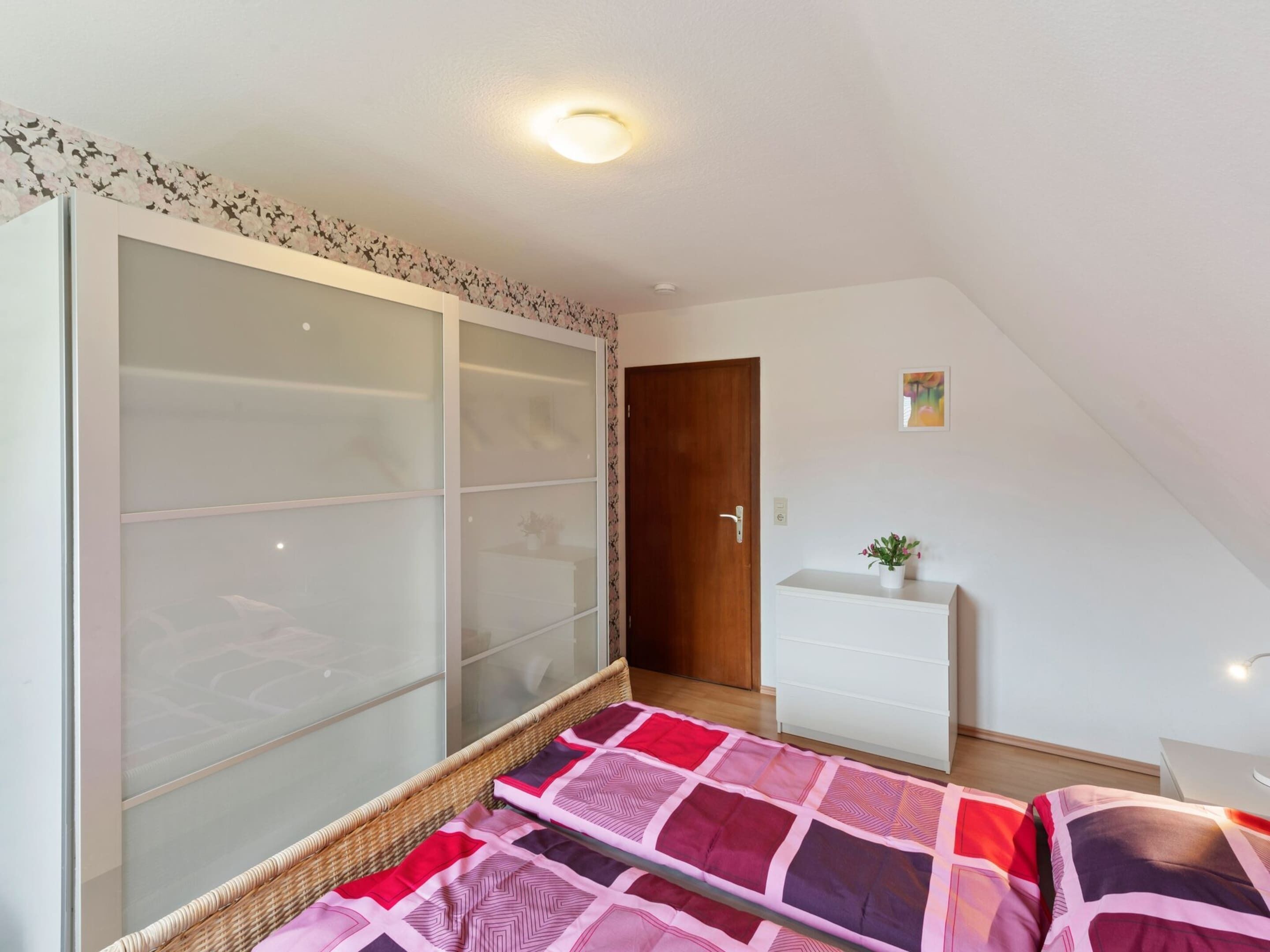 Une chambre à coucher avec un lit, une armoire, une commode et une porte.