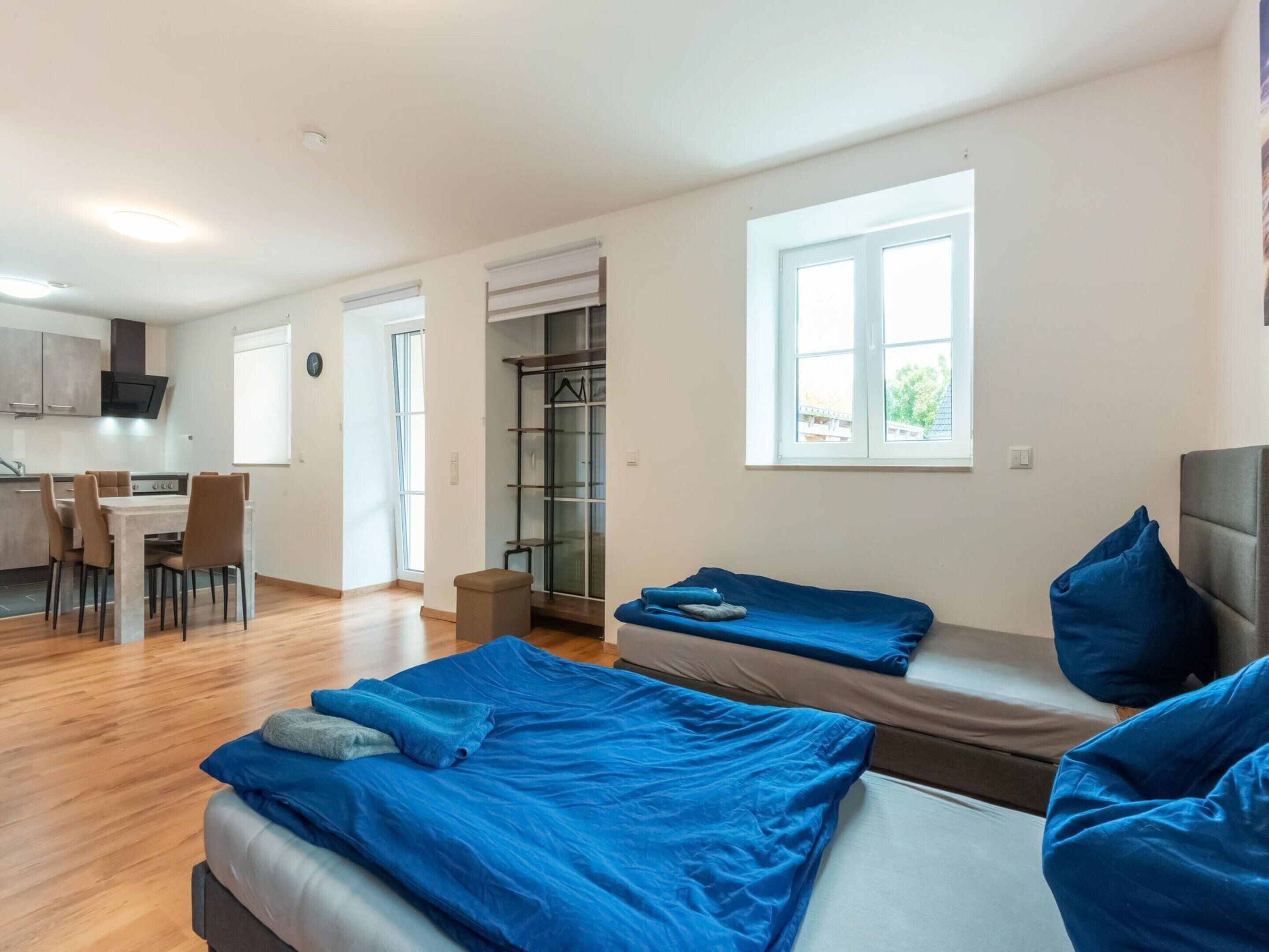 A modern apartment with two beds, a dining area, and a kitchen.