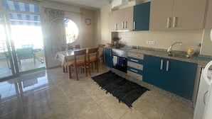 A modern kitchen with a dining area, featuring a granite countertop, stainless steel appliances, and a black rug. - Apartments LAS CARACOLAS, Puerto de Mogán 1C (Puerto de Mogán)