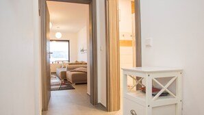 Ein Flur, der in einen Wohnbereich mit einer Couch, einem kleinen Tisch und einem weißen Schrank führt.