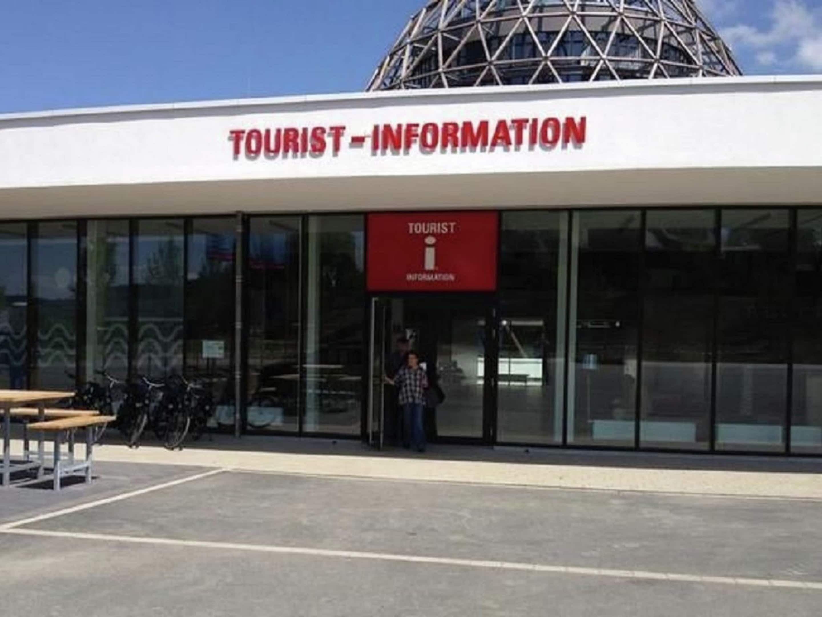 A Tourist Information building with a modern design, featuring large glass windows and a prominent dome structure.