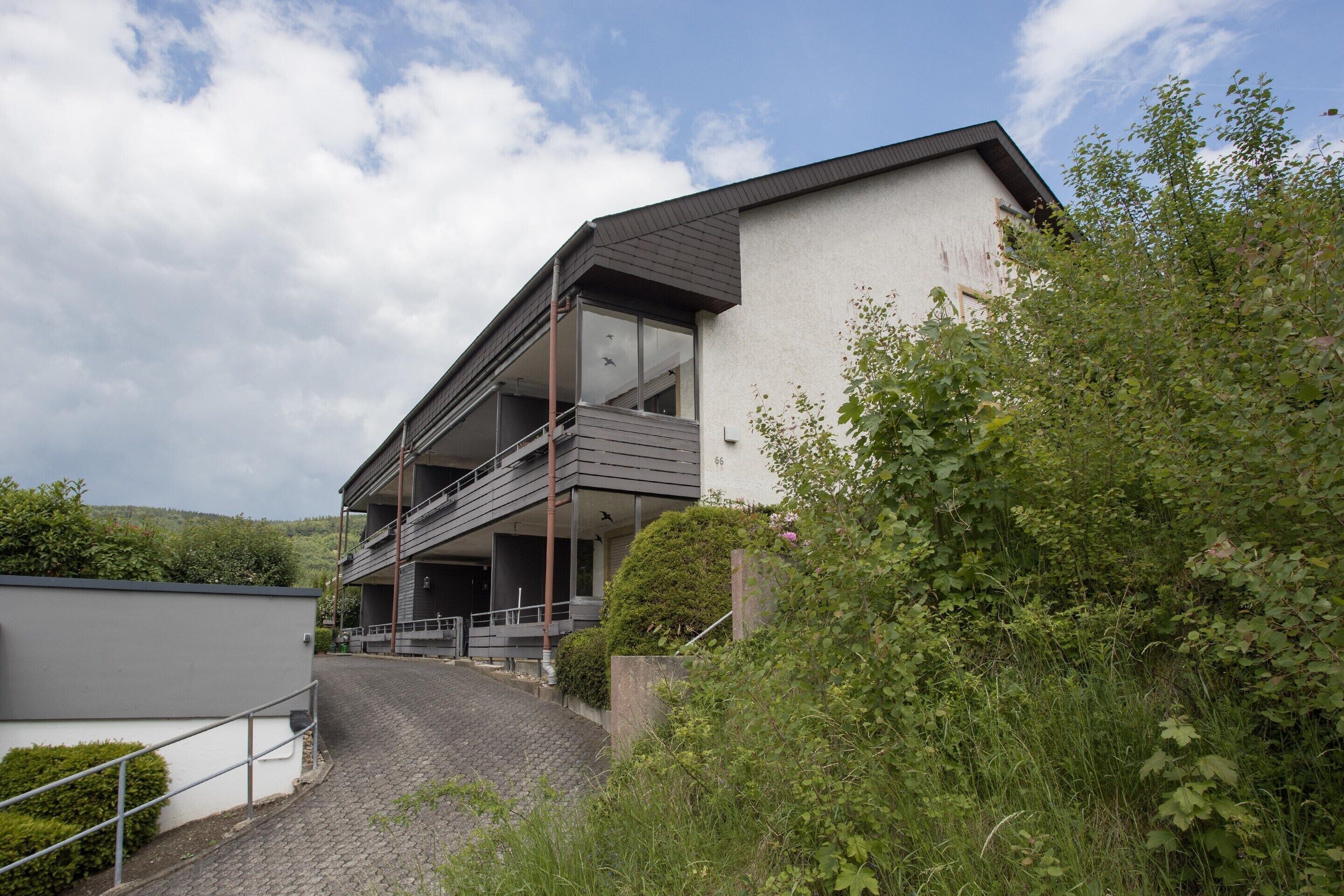 A modern two-story building with a flat roof, large windows, and a balcony.