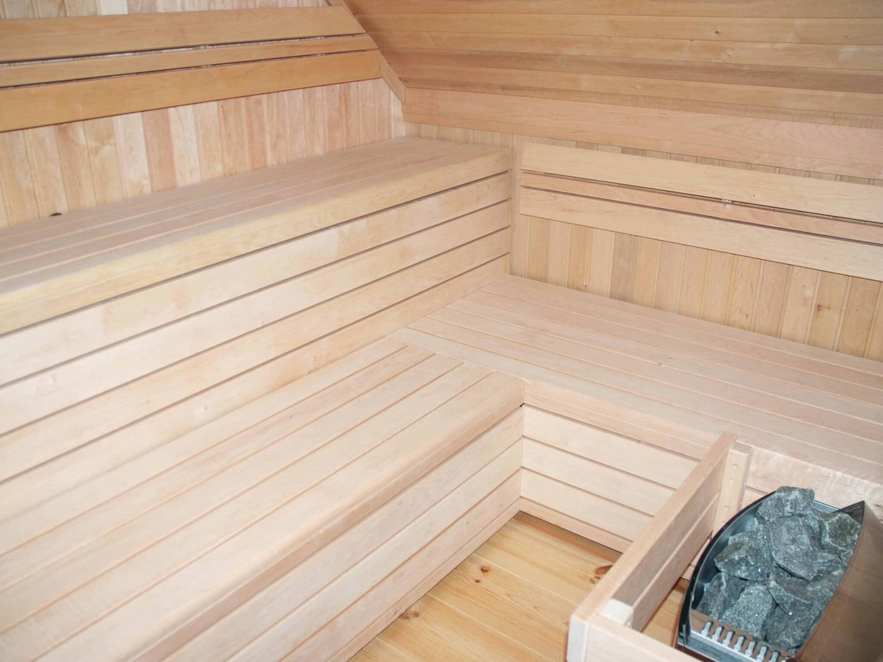 A sauna with wooden benches and a stone heating element.