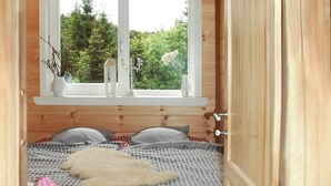 A cozy bedroom with a checkered bedspread, a fluffy rug, and a window with a view of greenery. - Forest Escape Near Ski Lift (Medebach)