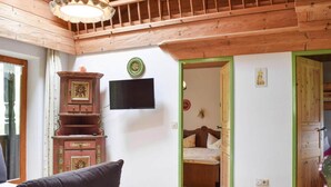 A wooden interior with a bed, a television, and a cabinet. - Cosy Flat in Schonau am Konigssee (Schoenau am Koenigssee)