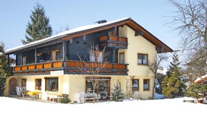 A two-story chalet with a balcony, wooden railings, and a snow-covered ground. - Cosy Flat in Schonau am Konigssee (Schoenau am Koenigssee)