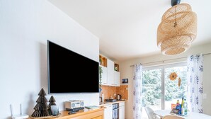 Une cuisine moderne dotée d’un téléviseur à écran plat, de meubles en bois et d’un coin repas avec une table et des chaises.