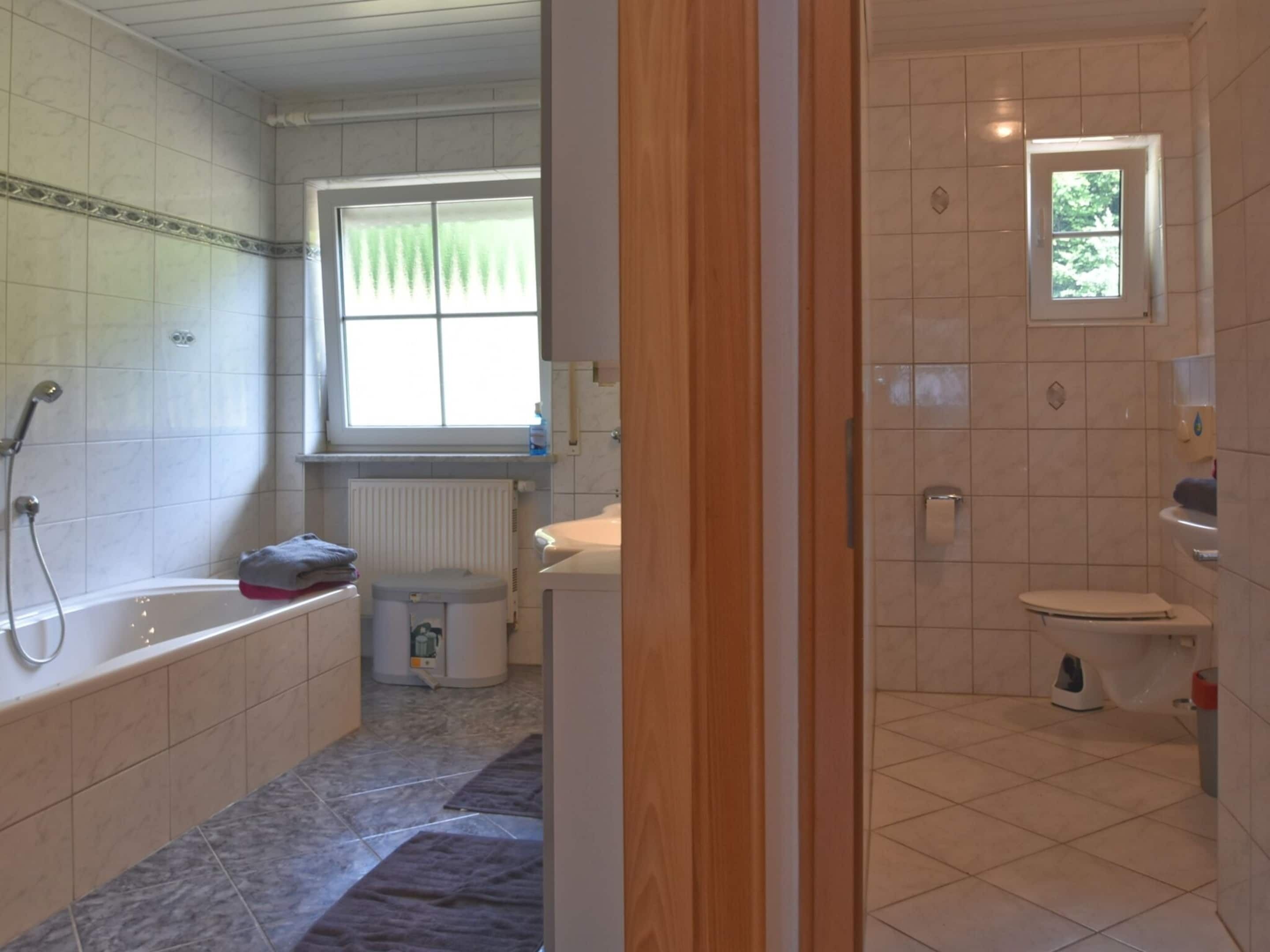 Ein Badezimmer mit Badewanne, Toilette und Fenster.