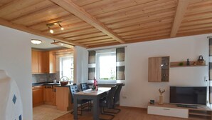 A modern kitchen with wooden cabinets and a dining area with a table and chairs. - Apartment in the Bavarian Forest (Zenting)