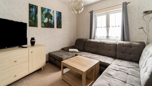En moderne stue med sofa, sofabord, fjernsyn og kunst på væggen.