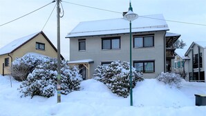 A two-story house with a snow-covered roof and surrounding bushes. - Wohnung Nahe Inselsberg Wanderwege (Waltershausen)