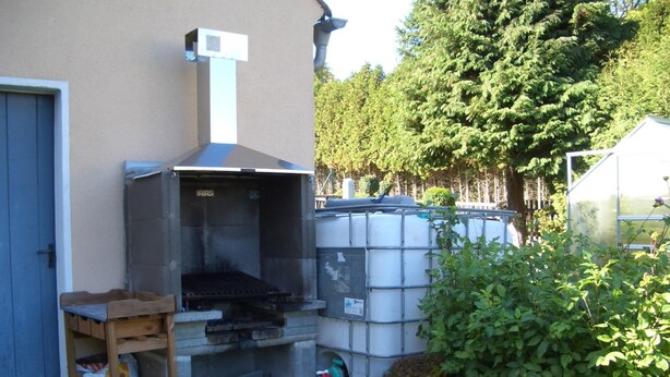 A small outdoor kitchen area with a grill, a water tank, and a green bucket. - Apartment in the Fichtelgebirge (Arzberg)