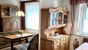 A cozy kitchen with wooden cabinets, a dining table, and a patterned armchair. - Apartment in the Fichtelgebirge (Arzberg)
