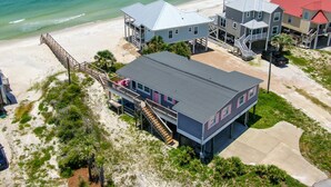 Una proprietà fronte mare con diversi edifici, tra cui una casa grande con un balcone e una struttura più piccola con tetto rosso.