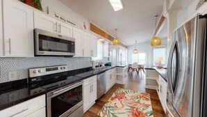 Una cucina moderna con mobili bianchi, elettrodomestici in acciaio inossidabile e piastrelle decorate.
