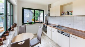 A modern kitchen with a dining area, large windows, and a view of the outside. - Forest Escape With Terrace (Eisfeld)
