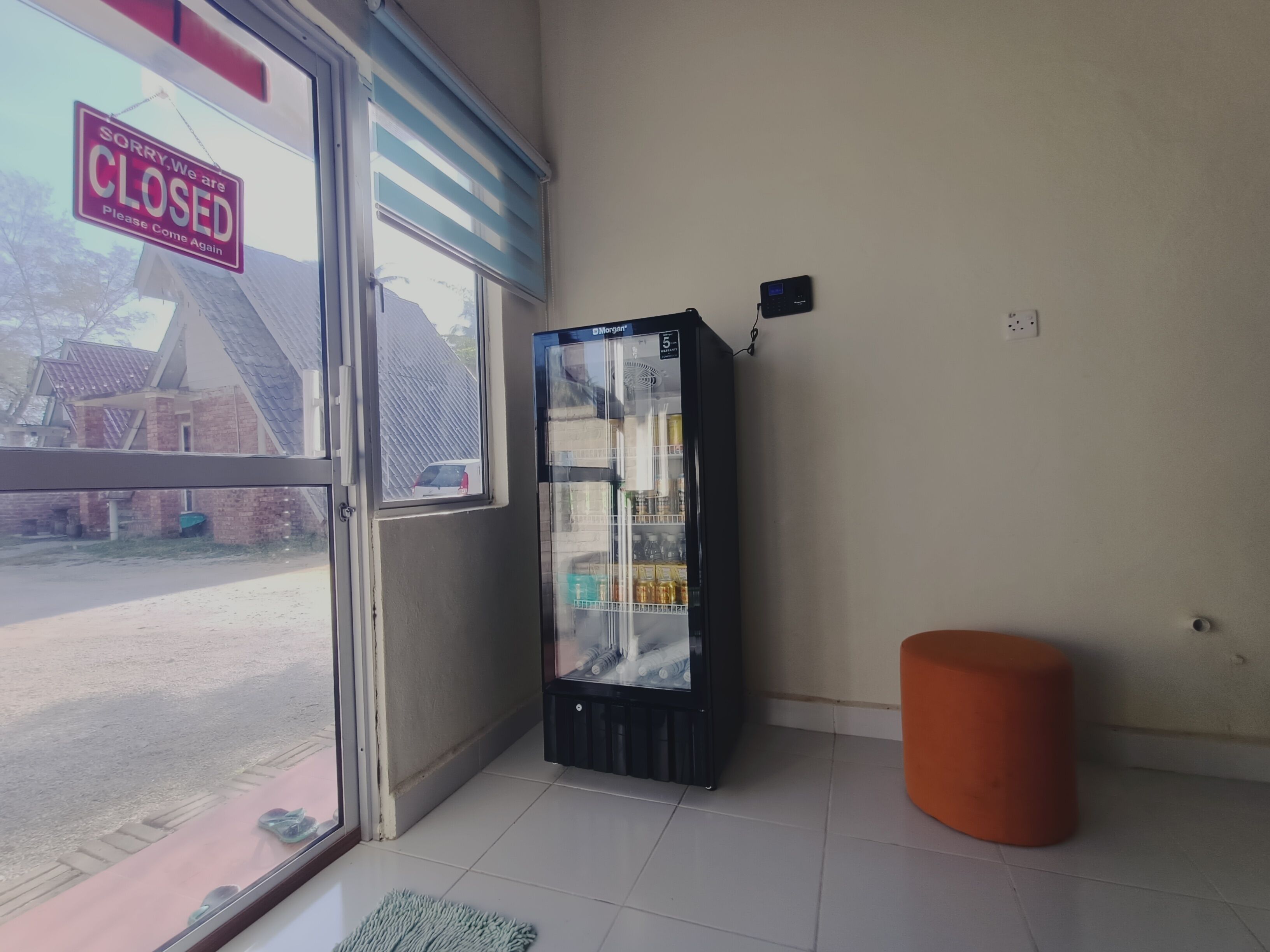 A closed storefront with a Morgan refrigeration unit and a small orange ottoman.
