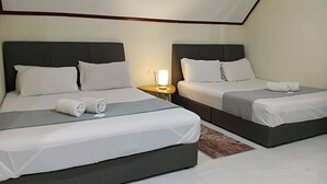 Dos camas individuales con cabeceros oscuros, ropa de cama blanca y una mesita de noche con lámpara.