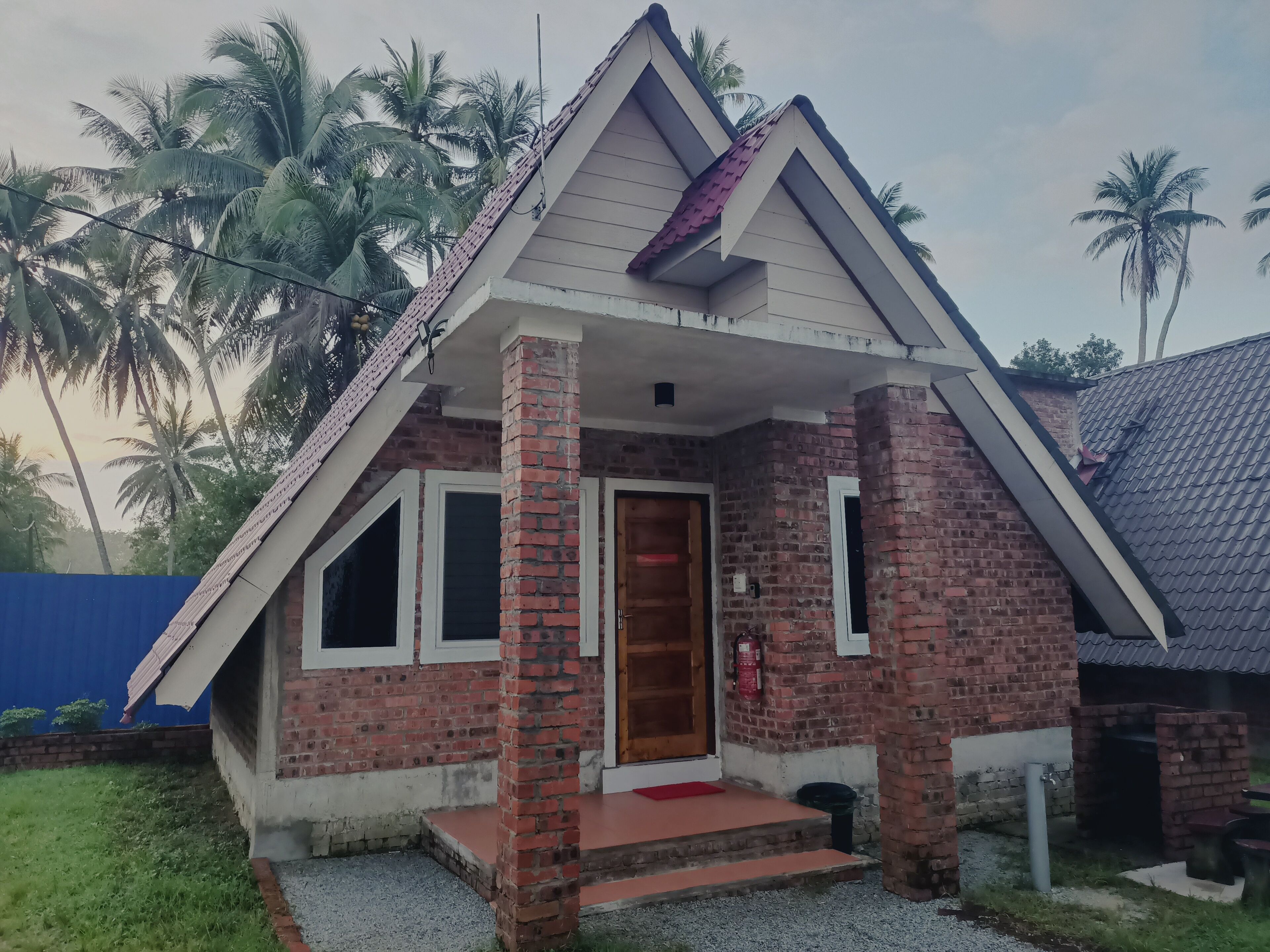 A small brick house with a pitched roof, a front porch, and a door.