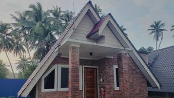 A small brick house with a pitched roof, a front porch, and a door.