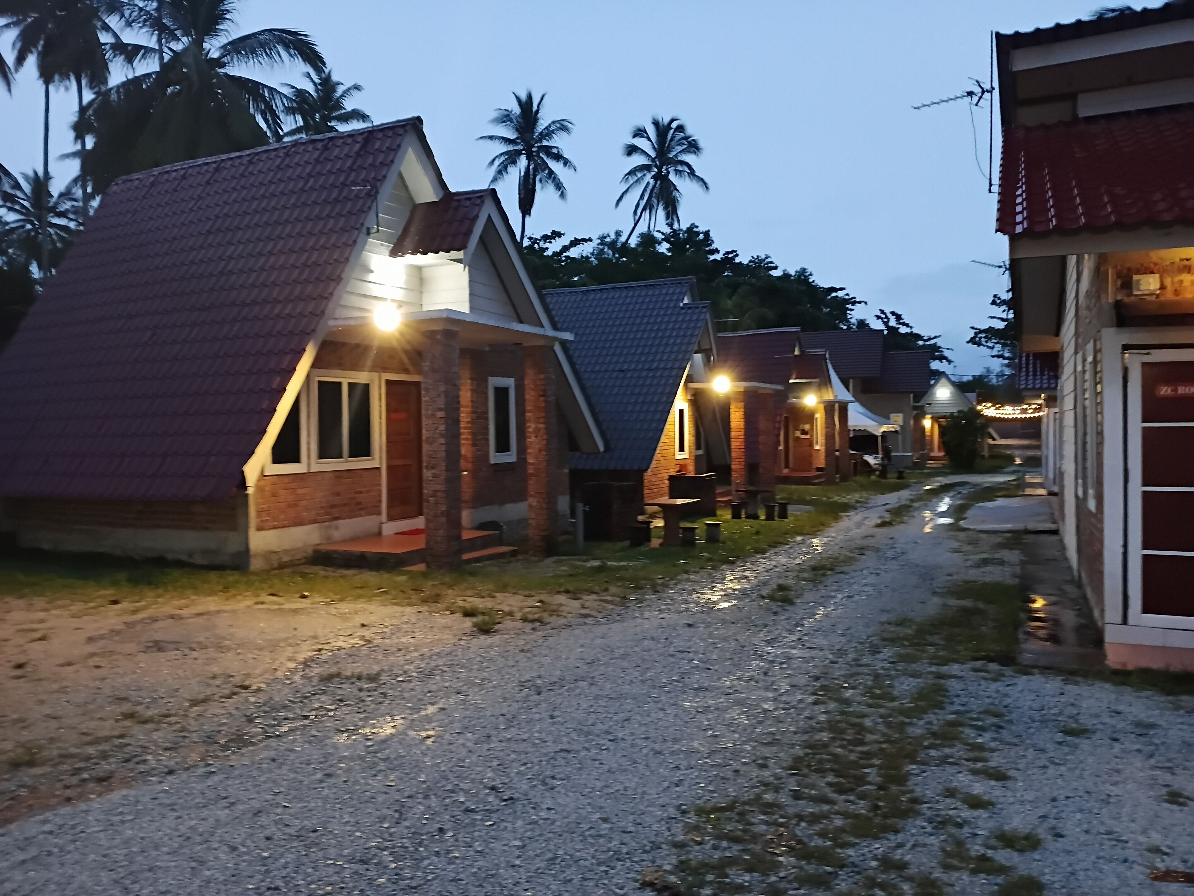 A row of small, single-story cottages with brick exteriors and pitched roofs, connected by a gravel path.